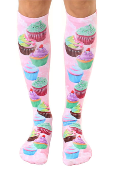 Pink knee-high socks with a photo-real print of pastel-frosted cupcakes scattered cuff to toe.