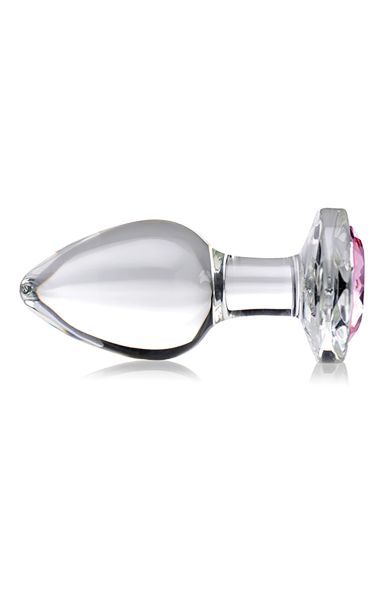 Clear glass butt plug standing upright on its pink-jeweled flared base showing teardrop shape and narrow neck.