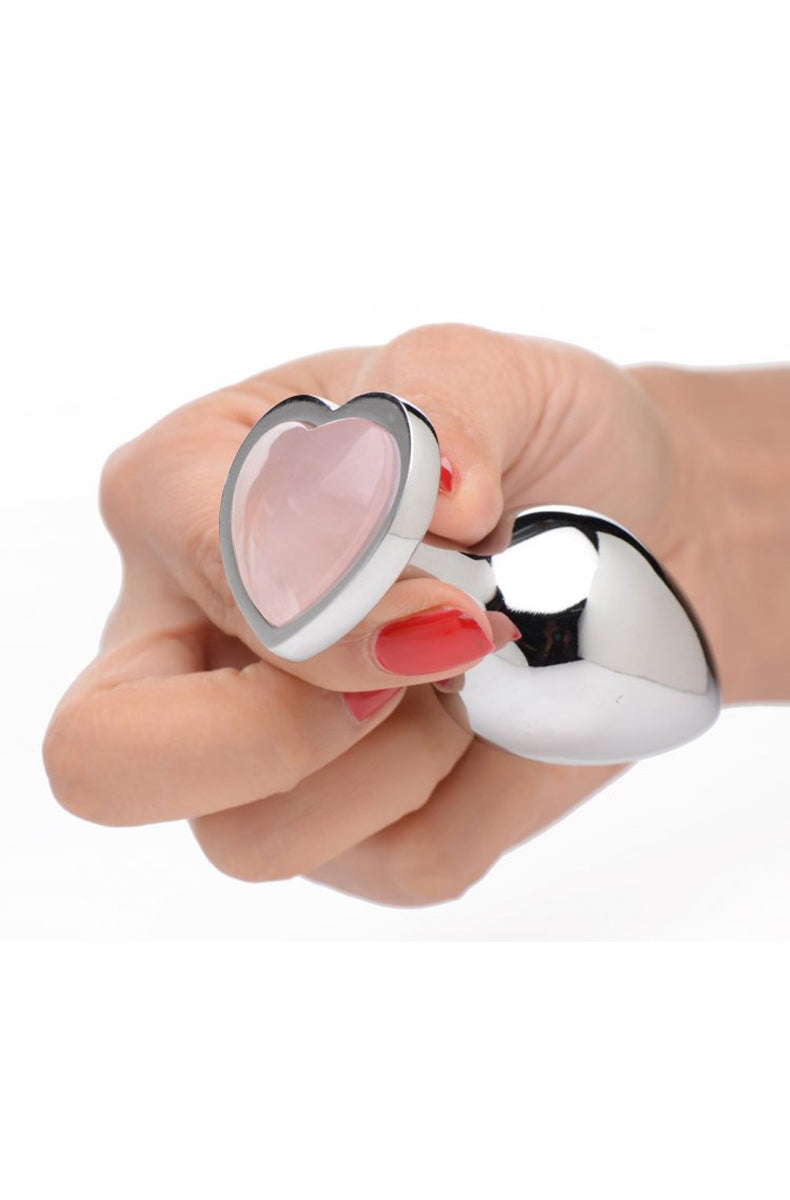 Hand with red nails holding the rose quartz heart base of a silver metal plug