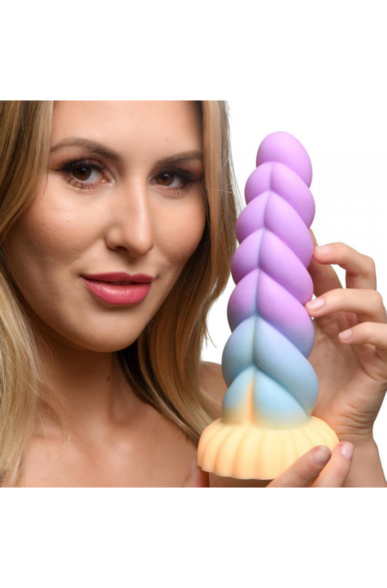 Pastel unicorn silicone dildo held in a hand for size reference.