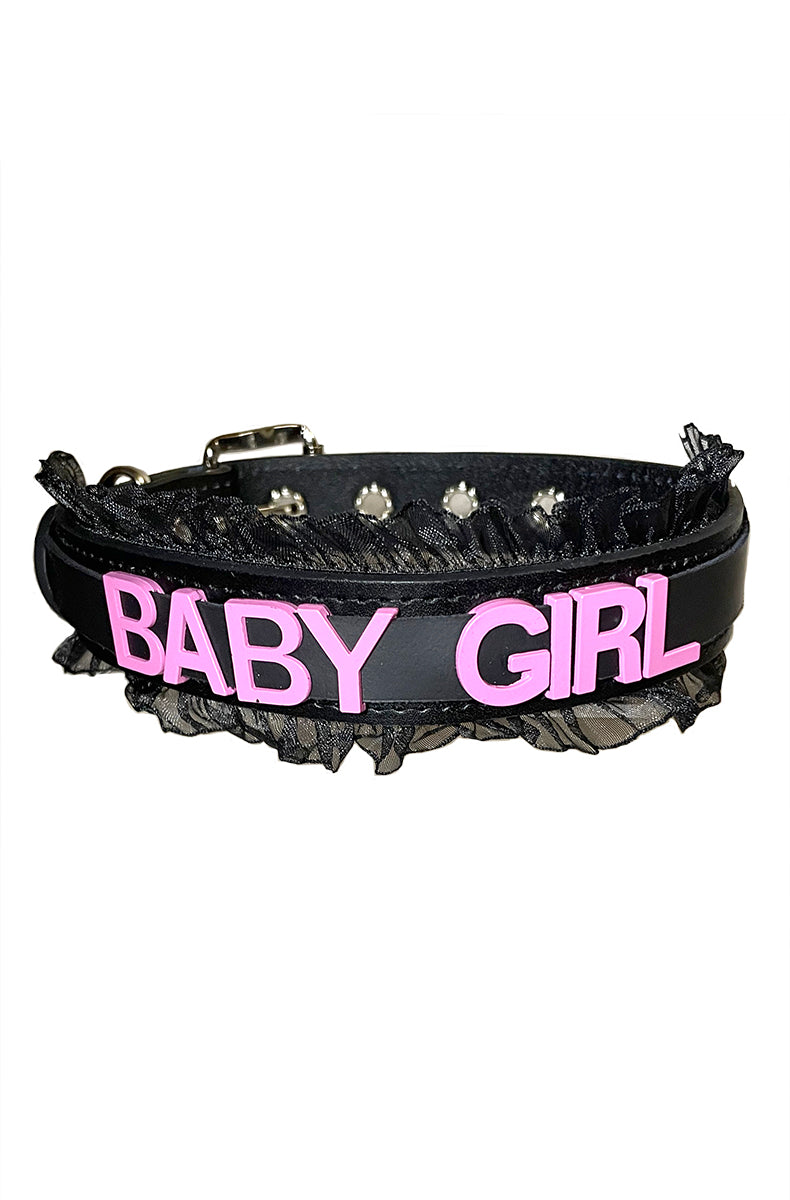 Black vegan-leather collar with "BABY GIRL" in bold pink lettering, finished with a black sheer organza ruffle along the top and bottom edges.