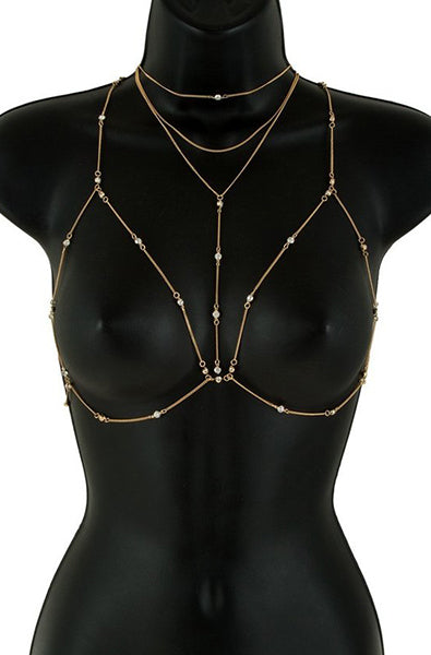 Gold-tone body chain bra with rhinestone-bezel chains forming open bra triangles, paired with a layered triple-strand choker, displayed on a black bust form.