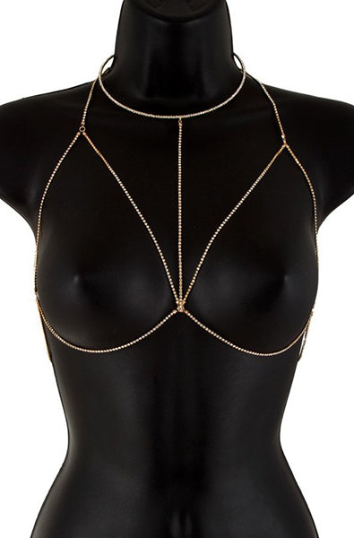 Gold-tone body chain bra with double-strand chains and clear rhinestone bezels outlining the bra triangles, on a black bust form.