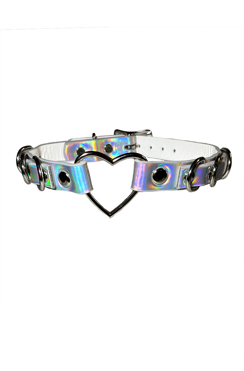 Holographic silver vegan-leather collar with a large silver heart-shaped open ring at the front, silver D-rings, and grommet eyelets along the strap.