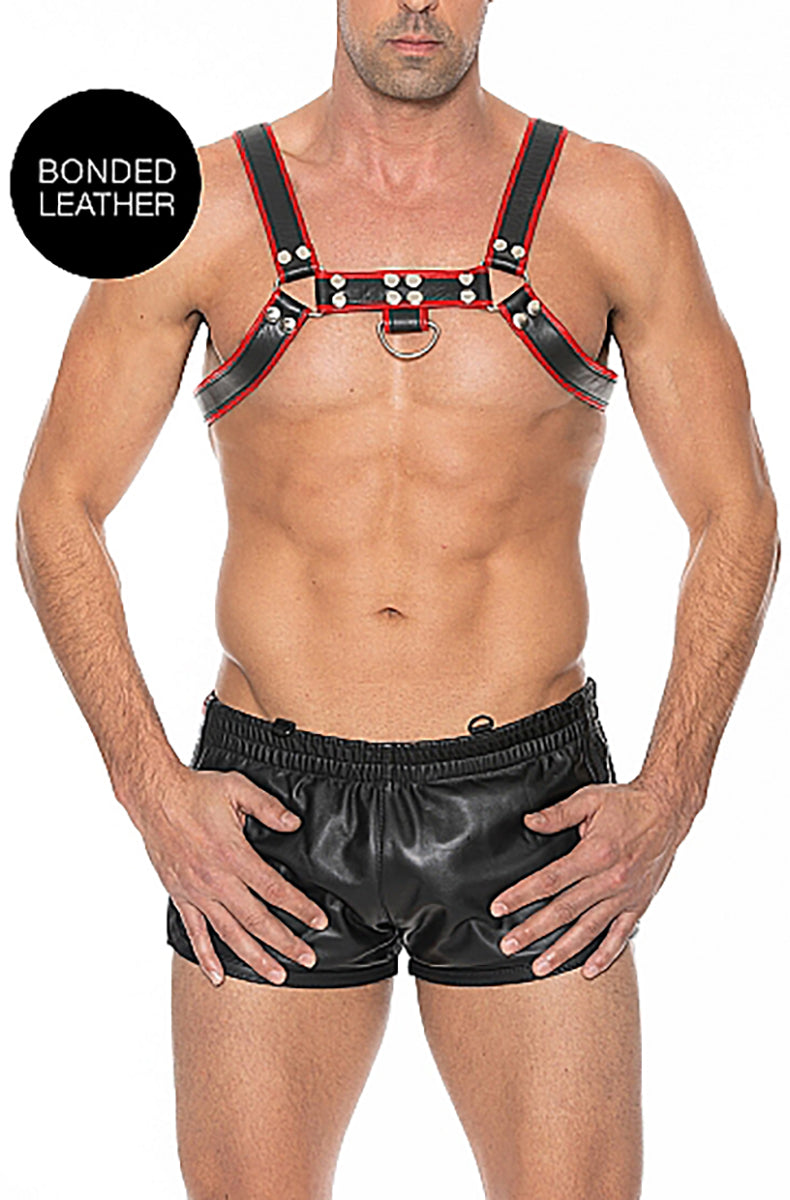 Black bonded leather bulldog chest harness with red trim, silver-tone D-rings, and a center-chest O-ring, on a male model.