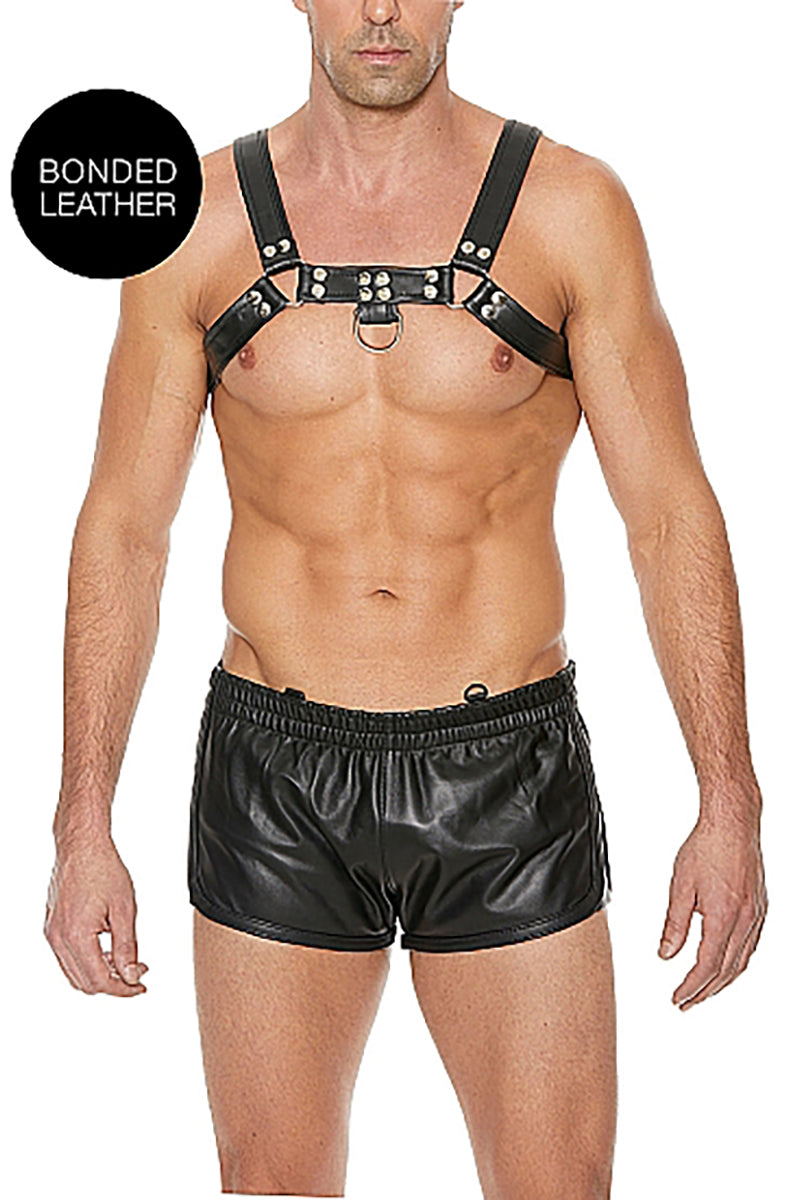 Male model wearing all-black bonded leather bulldog chest harness, double shoulder straps meeting at a center-chest O-ring.