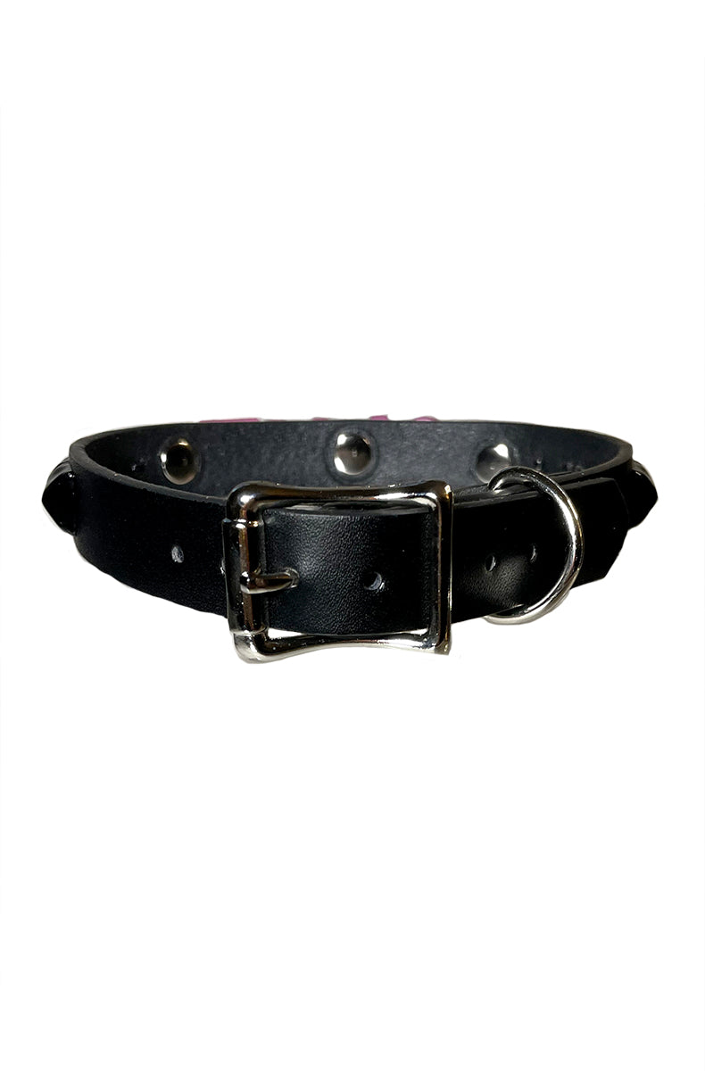 Black vegan leather collar with raised pink SLUT lettering, black pyramid studs, and a silver D-ring with attached O-ring at the front.