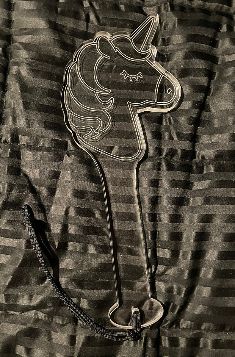 Clear cast acrylic paddle in a unicorn-head silhouette with horn, etched mane, and closed eyelash detail.